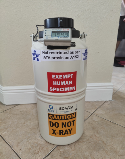 Close-up of an MVE cryogenic cylinder for transporting embryos with a digital data logger displaying -194.9°C and warning labels stating “Do not X-ray.”